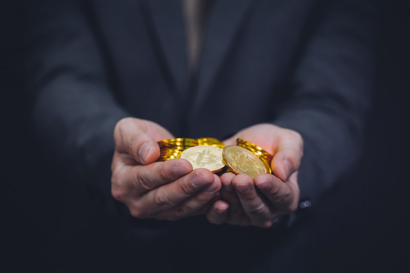 businessman-s-hands-full-of-bitcoin-sign-of-coins-2022-12-16-09-59-43-utc.jpg